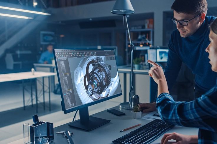 Engineer Working on Desktop Computer, Screen Showing CAD Software with Engine 3D Model, Her Male Project Manager Explains Job Specifics Industrial Design Engineering Facility Office