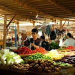 A bustling indoor market showcasing vibrant fresh produce stands in warm lighting.