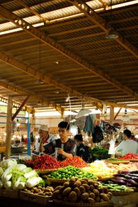 A bustling indoor market showcasing vibrant fresh produce stands in warm lighting.