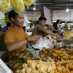 A busy street food market with vendors selling traditional snacks to customers.