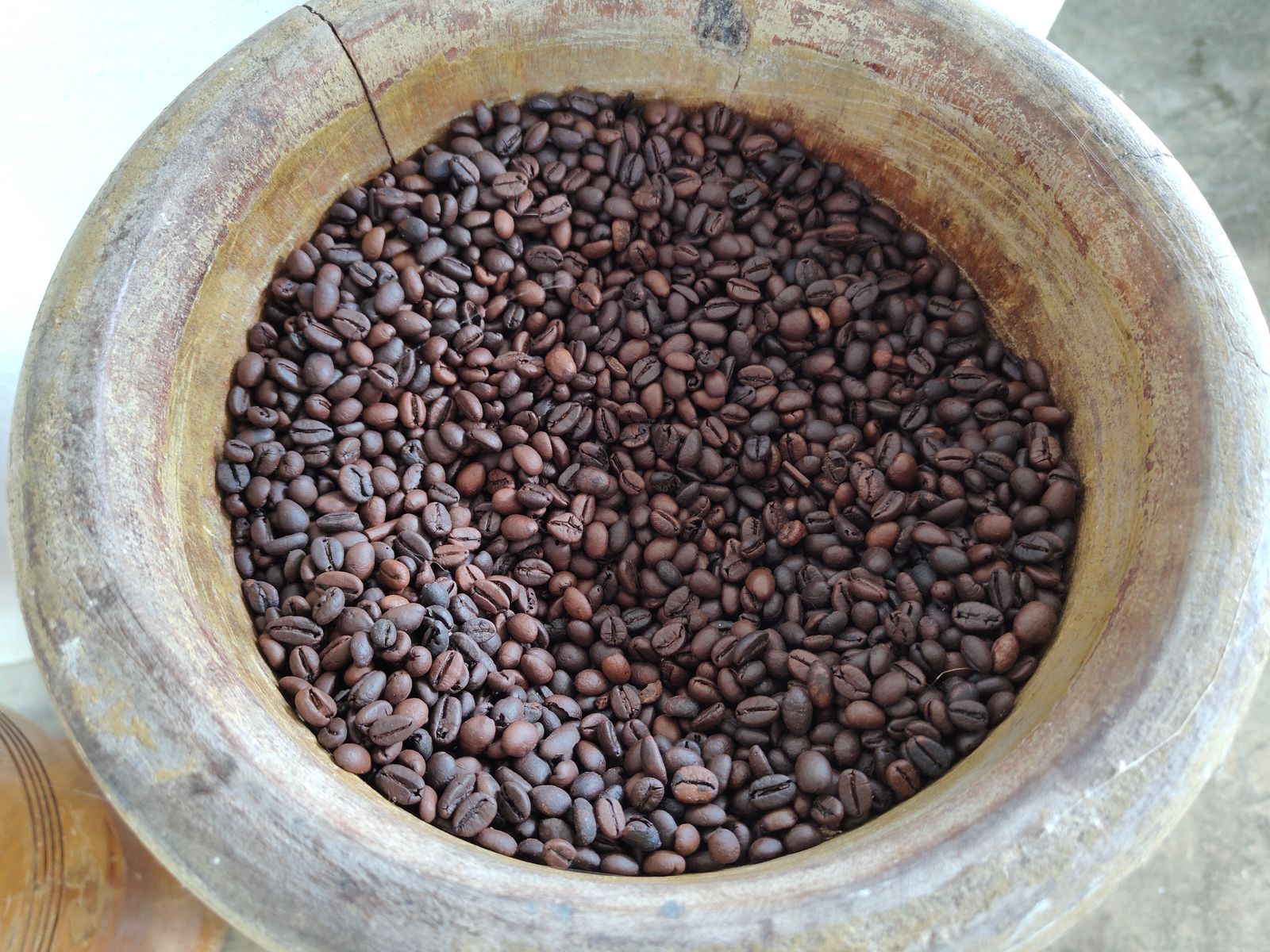 A close-up of roasted coffee beans in a rustic wooden bowl, highlighting texture and color.