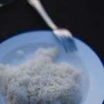 A close-up view of rice served with stainless steel fork and spoon on a plate.