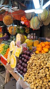 A colorful display of tropical fruits at a market stall in the Philippines, showcasing durian, oranges, and jackfruit.