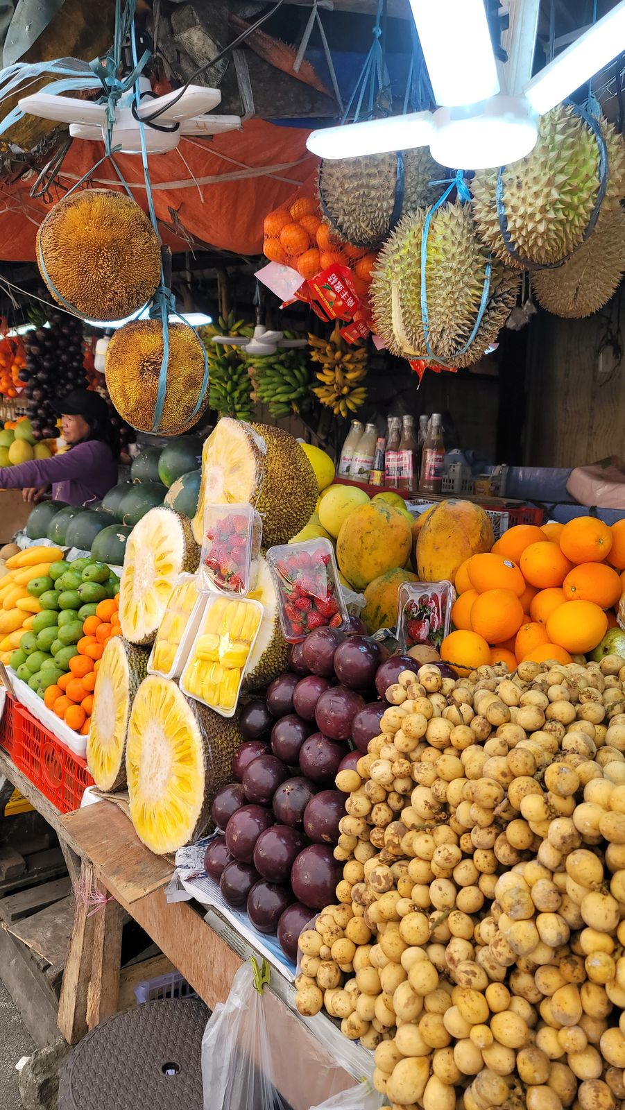 A colorful display of tropical fruits at a market stall in the Philippines, showcasing durian, oranges, and jackfruit.