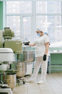 A food industry worker in a modern kitchen using an industrial mixer with protective gear.