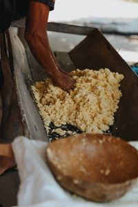 A person manually working with cassava dough in a rustic setting, showcasing traditional food preparation.