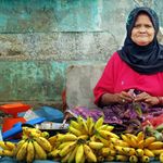 An elderly woman selling fresh bananas at a traditional market in North Sumatra, Indonesia.
