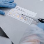 Close-up of a scientist using pipette on sample cards in the lab.