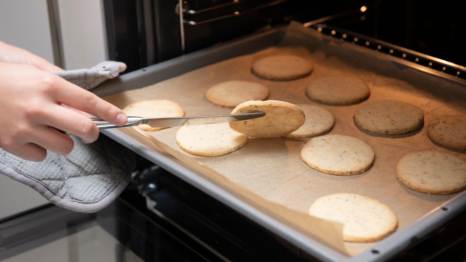 Close-up of cookies on a tray being baked in a kitchen oven.