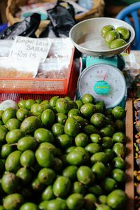 Close-up of fresh green mangoes displayed on a market stall with scales, highlighting vibrant produce.
