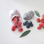 Close-up of frozen raspberries, blueberries, and strawberries on a white surface.