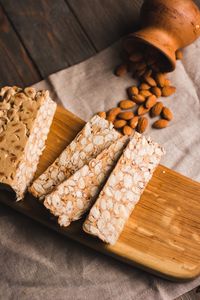 Close-up of peanut brittle slices on a wooden board with almonds, showcasing delicious texture and composition.