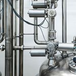 Close-up of stainless steel machinery and pipes in an industrial setting, showcasing modern engineering.