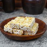 Close-up of traditional puffed rice cakes on a rustic wooden plate against rustic pottery in a cozy setting.