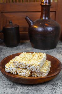 Close-up of traditional puffed rice cakes on a rustic wooden plate against rustic pottery in a cozy setting.