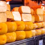Close-up of various cheeses wrapped and displayed on a market shelf.