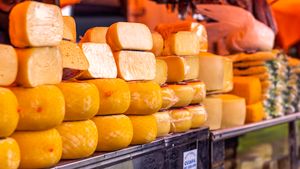 Close-up of various cheeses wrapped and displayed on a market shelf.
