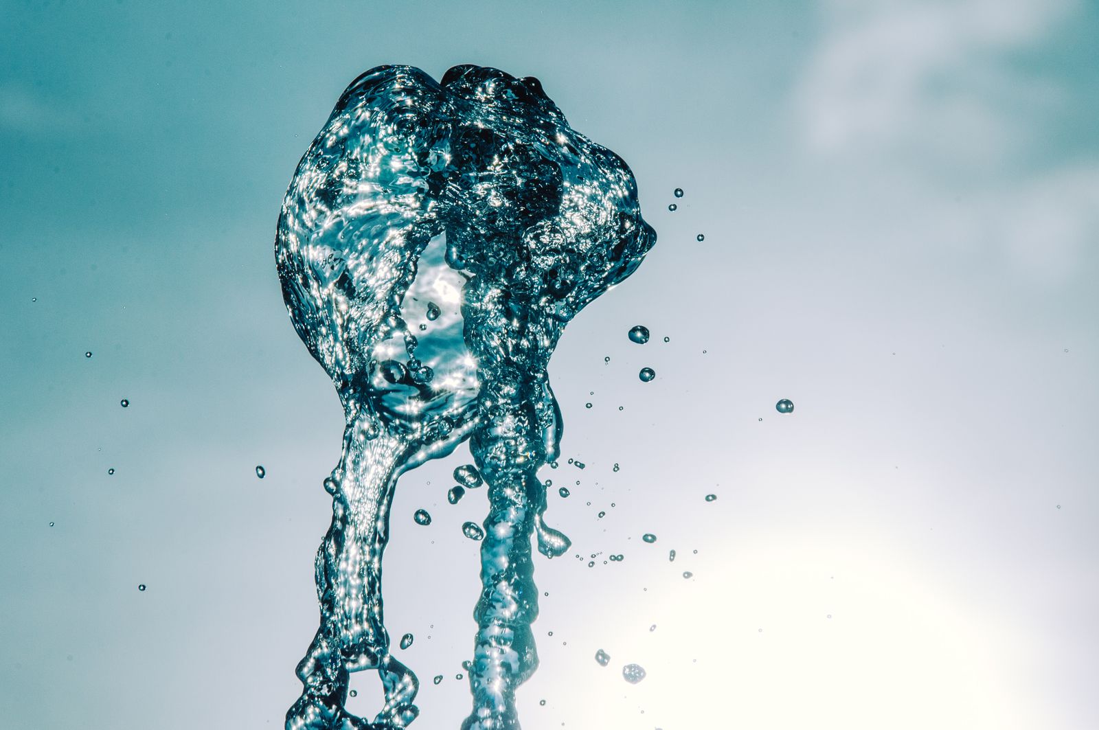 Close-up of water splash in mid-air against a bright sky, capturing motion and transparency.