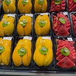 Colorful display of packaged mango and watermelon slices in a market setting.