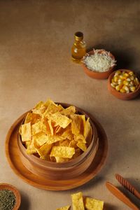 Crispy corn chips in a wooden bowl with cheese, corn, and herbs.