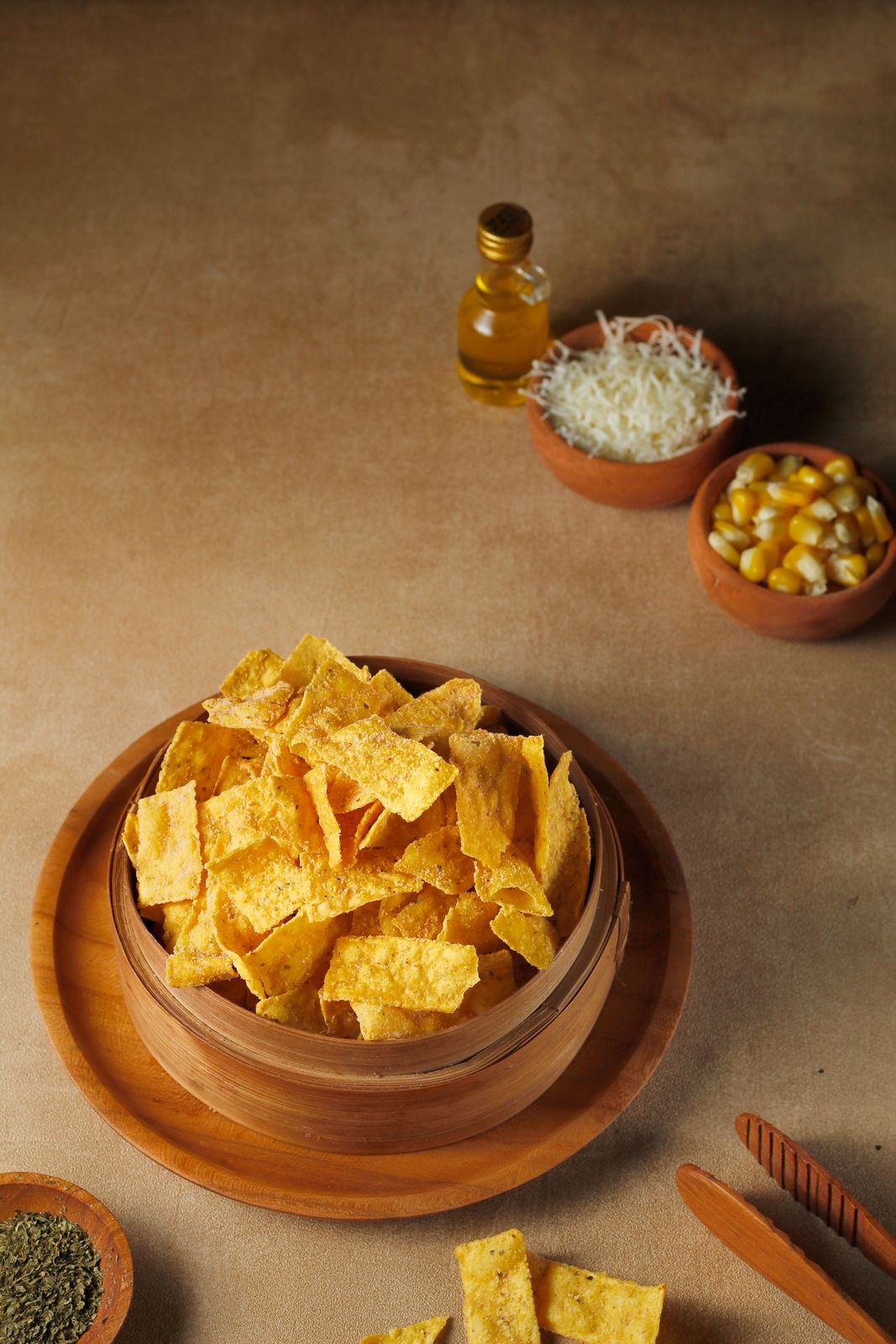 Crispy corn chips in a wooden bowl with cheese, corn, and herbs.