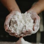 Crop anonymous female preparing and showing white clean flour in hands in kitchen