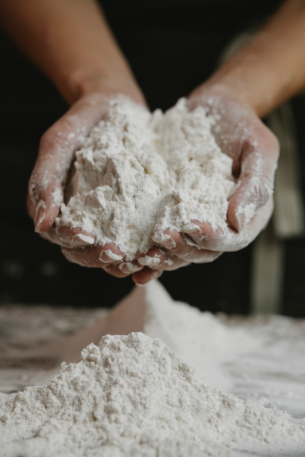 Crop anonymous female preparing and showing white clean flour in hands in kitchen