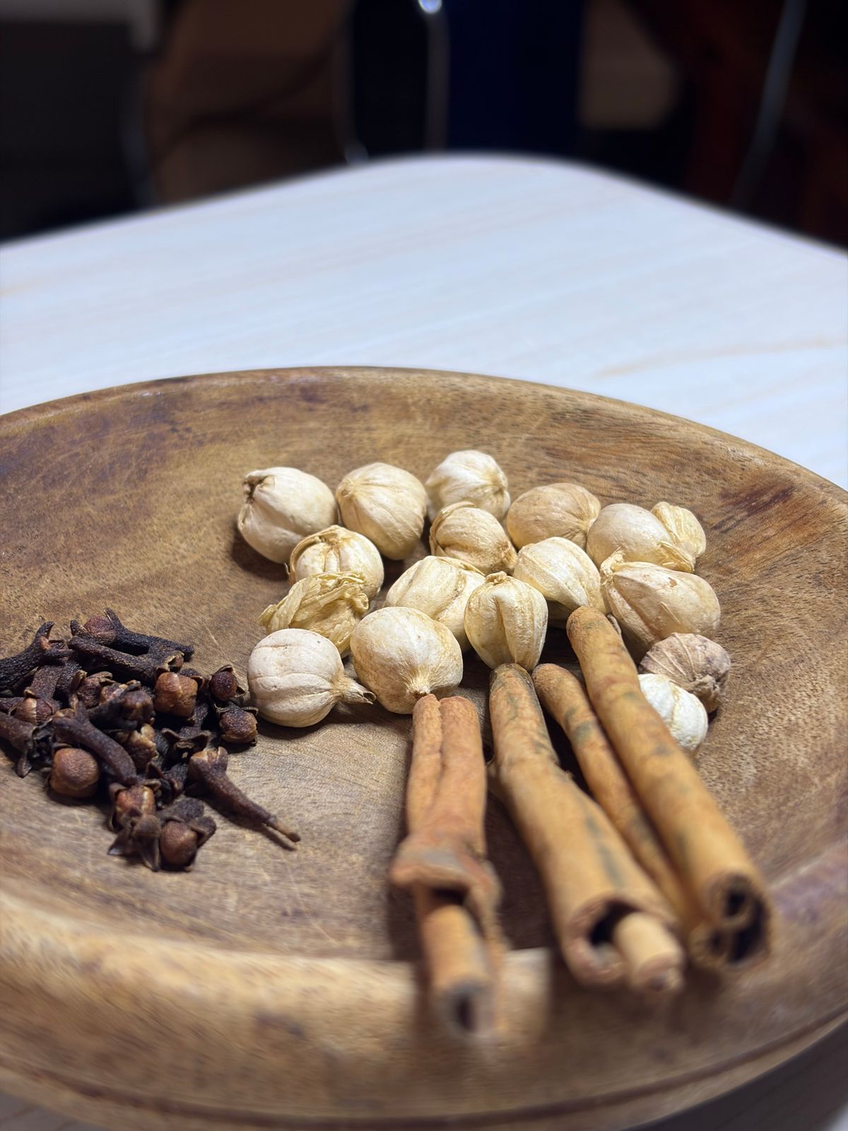 Detailed view of spices including cloves, cardamom, and cinnamon on a wooden plate.