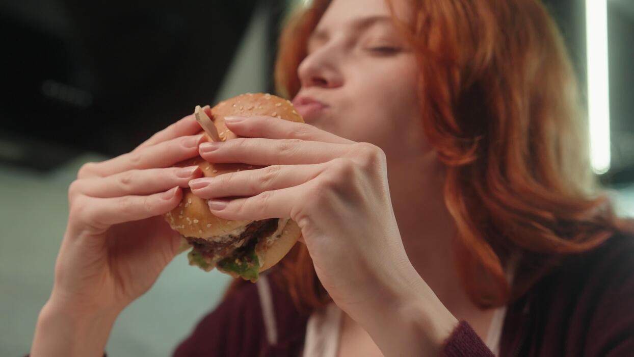 Imgi 171 happy hungry caucasian woman female girl client customer eat chew tasty burger eating delicious juicy hamburger enjoy chewing cheeseburger indoo