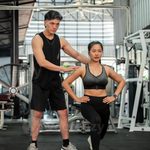 Imgi 195 a professional asian male fitness coach is training a female client in a gym checking her form photo