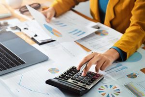 Imgi 376 woman accountant use calculator and computer with holding pen on desk in office finance and accounting concept free photo