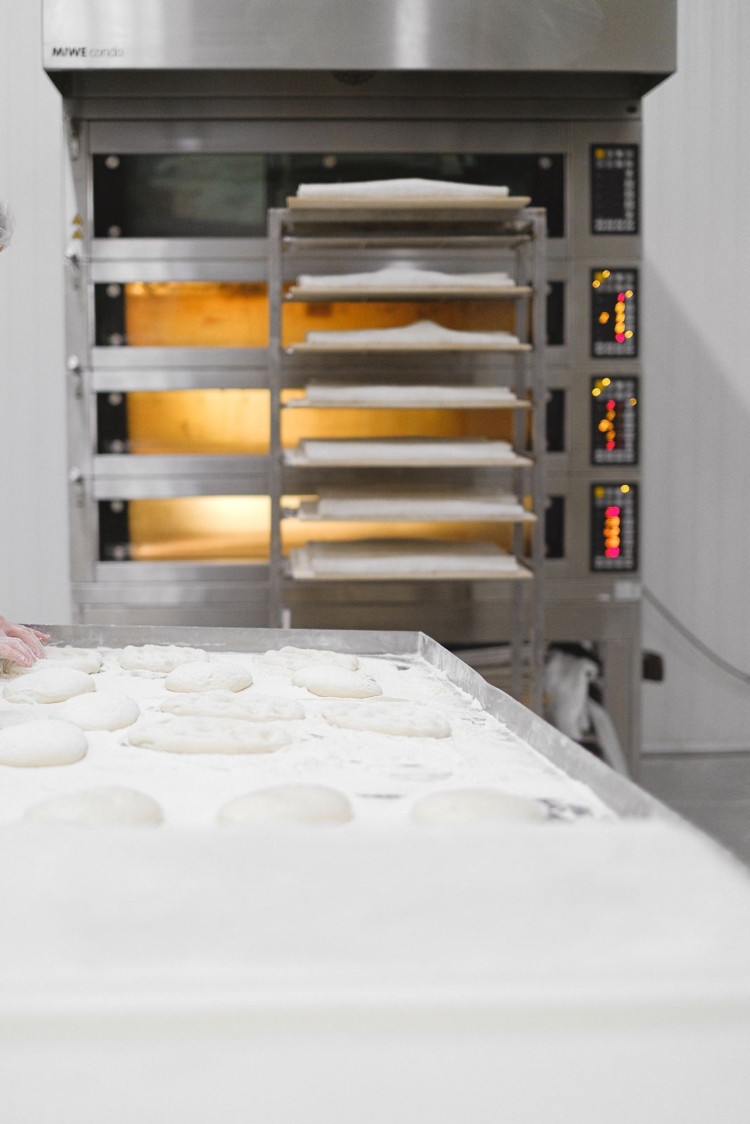 Industrial bakery scene with dough preparation and multi-shelf oven heating.