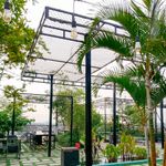 Spacious outdoor patio with lush greenery, pergolas, and vintage lighting, perfect for relaxation.