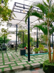 Spacious outdoor patio with lush greenery, pergolas, and vintage lighting, perfect for relaxation.