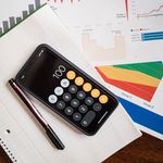 Top view of financial reports with a calculator app open on a smartphone.