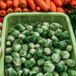 Vibrant display of fresh Brussels sprouts, carrots, and vegetables at a Mexican farmers market.