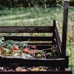 Wooden compost bin in an Estonian garden with organic waste and vegetables.