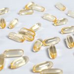 Close-up of yellow transparent softgel capsules on a white background, suitable for pharmaceutical or supplement themes.