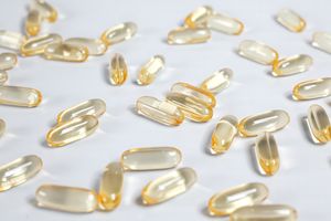 Close-up of yellow transparent softgel capsules on a white background, suitable for pharmaceutical or supplement themes.